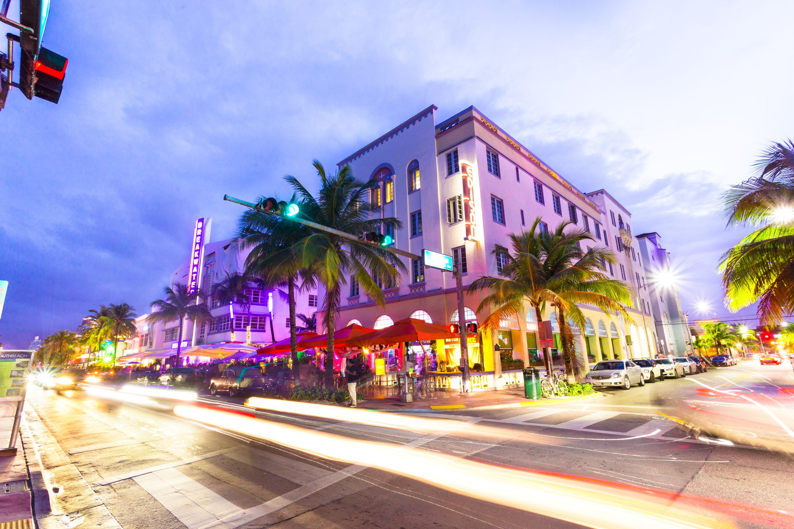 Ocean Drive scene at sunset with lights, palm trees, cars and pe